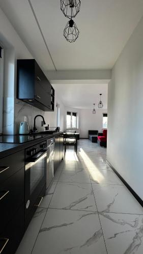 a kitchen with black cabinets and a living room at Mieszkanie na wyłączność in Radomsko