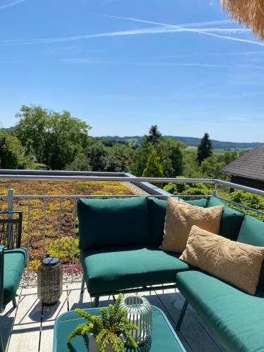 a green couch on a balcony with a view at Moderne Ferienwohnung Nähe Bad Griesbach, Haarbach in Haarbach