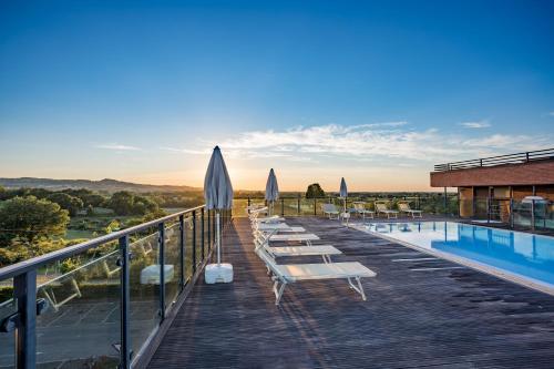 a deck with tables and umbrellas next to a pool at Grand Hotel Forlì in Forlì