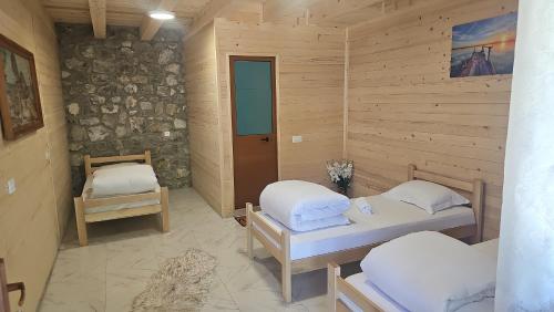 a room with two beds and a stone wall at Ekoo katun Jezerca in Vusanje