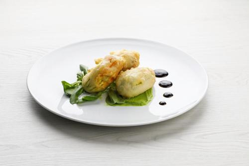 a plate of food with dumplings and greens on a table at MICHELINO 75 by the Sydney Hotel in Bologna