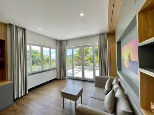 Una sala de estar con un sofá y algunas ventanas. en Ruby Villa, en Nha Trang
