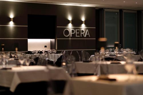 a restaurant with white tables and chairs and a sign that says opera at MICHELINO 75 by the Sydney Hotel in Bologna