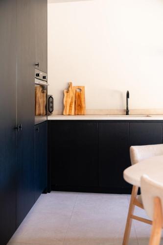 a kitchen with black cabinets and a table at VAKANTIEDOMEIN DOUVE in Heuvelland