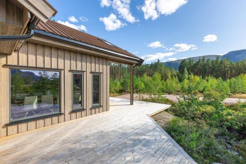 a house with a deck with a view of the mountains at Det Kosekroken – Nordic Style Holiday Home by the Fjord in Vradal