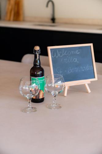 a bottle of wine and two wine glasses on a table at VAKANTIEDOMEIN DOUVE in Heuvelland