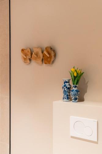 a shelf with two vases and flowers on a wall at VAKANTIEDOMEIN DOUVE in Heuvelland