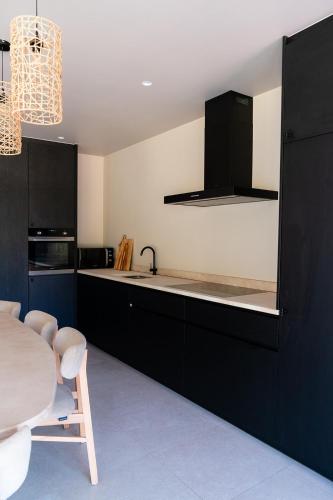 a kitchen with black cabinets and a sink and a table at VAKANTIEDOMEIN DOUVE in Heuvelland