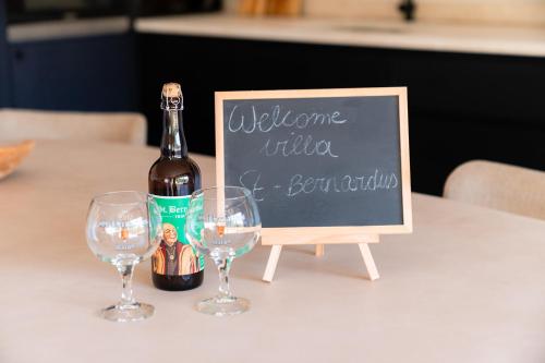 a bottle of wine and two wine glasses on a table at VAKANTIEDOMEIN DOUVE in Heuvelland