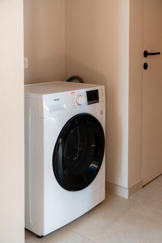 a white washing machine in a corner of a room at VAKANTIEDOMEIN DOUVE in Heuvelland