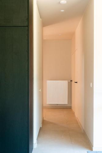 an empty hallway with a green door and a radiator at VAKANTIEDOMEIN DOUVE in Heuvelland