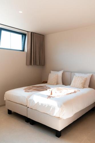 a bedroom with a large white bed with a window at VAKANTIEDOMEIN DOUVE in Heuvelland