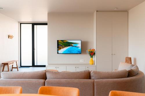 a living room with a couch and a tv on the wall at VAKANTIEDOMEIN DOUVE in Heuvelland