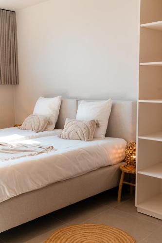 a bed with white sheets and pillows in a room at VAKANTIEDOMEIN DOUVE in Heuvelland