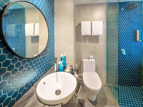 a bathroom with a sink and a toilet and a mirror at Quest Vibe Dewi Sri Bali in Legian