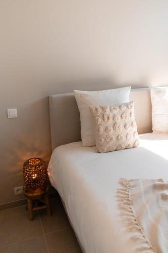 a bed with white sheets and a lamp on a table at VAKANTIEDOMEIN DOUVE in Heuvelland