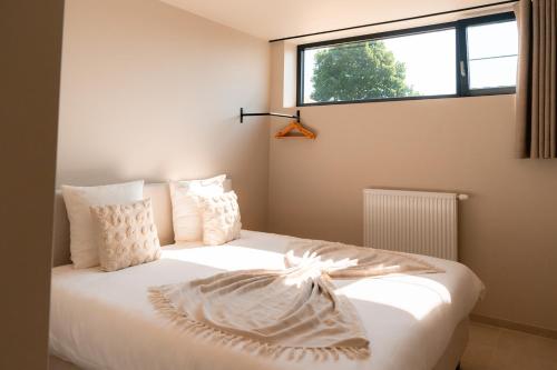 a bedroom with a white bed with a window at VAKANTIEDOMEIN DOUVE in Heuvelland