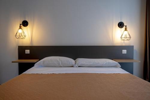 a bedroom with a bed with two pillows and two lights at Olympus in Avola