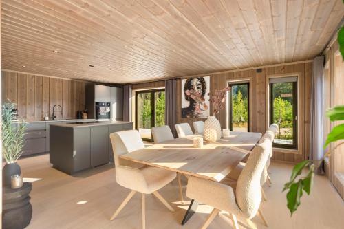 a kitchen and dining room with a wooden table and chairs at Det Kosekroken – Nordic Style Holiday Home by the Fjord in Vradal