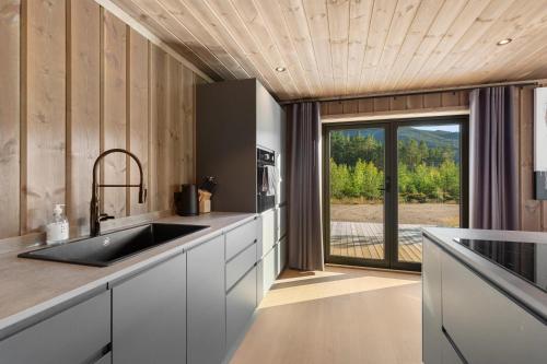 a kitchen with a sink and a large window at Det Kosekroken – Nordic Style Holiday Home by the Fjord in Vradal