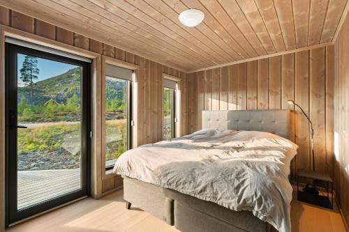 a bedroom with a bed and a large window at Det Kosekroken – Nordic Style Holiday Home by the Fjord in Vradal