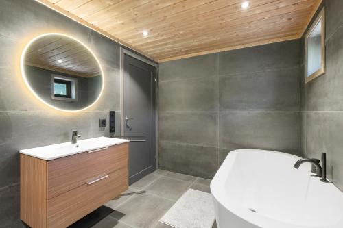 a bathroom with a white tub and a sink at Det Kosekroken – Nordic Style Holiday Home by the Fjord in Vradal