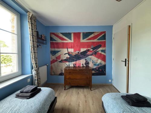 a room with two beds and a flag on the wall at Les continents maison spacieuse 4 belles chambres parking privatif terrasse à 5 mn à pied tous commerces et 20 mn plage Omaha Beach et à 15 mn de Bayeux in Le Molay-Littry