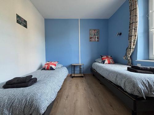 two beds in a room with blue walls at Les continents maison spacieuse 4 belles chambres parking privatif terrasse à 5 mn à pied tous commerces et 20 mn plage Omaha Beach et à 15 mn de Bayeux in Le Molay-Littry