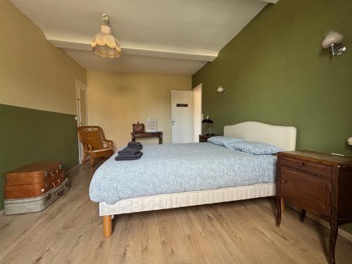 a bedroom with a bed and a dresser and green walls at Les continents maison spacieuse 4 belles chambres parking privatif terrasse à 5 mn à pied tous commerces et 20 mn plage Omaha Beach et à 15 mn de Bayeux in Le Molay-Littry