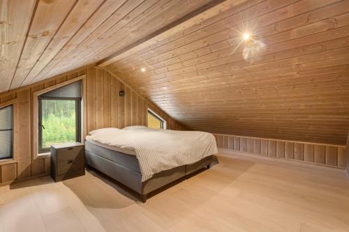 a bedroom with a bed in a room with wooden walls at Det Kosekroken – Nordic Style Holiday Home by the Fjord in Vradal
