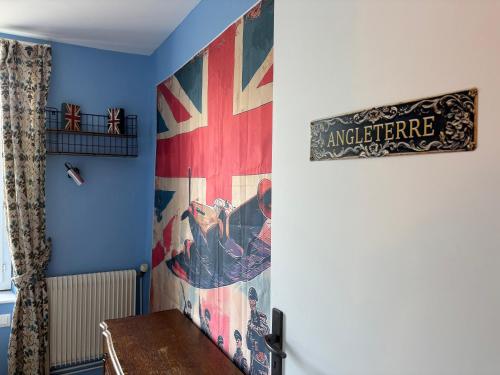 a room with a painting on the wall and a table at Les continents maison spacieuse 4 belles chambres parking privatif terrasse à 5 mn à pied tous commerces et 20 mn plage Omaha Beach et à 15 mn de Bayeux in Le Molay-Littry