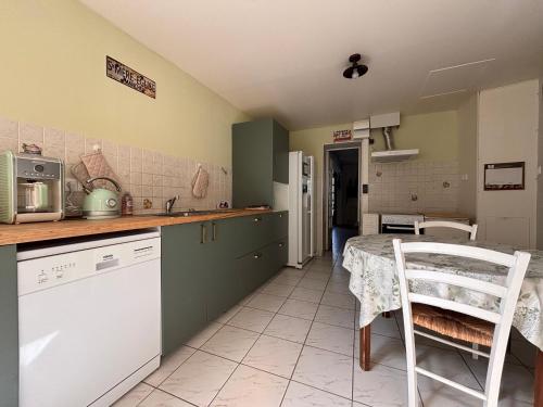 a kitchen with a table and a white chair in it at Les continents maison spacieuse 4 belles chambres parking privatif terrasse à 5 mn à pied tous commerces et 20 mn plage Omaha Beach et à 15 mn de Bayeux in Le Molay-Littry