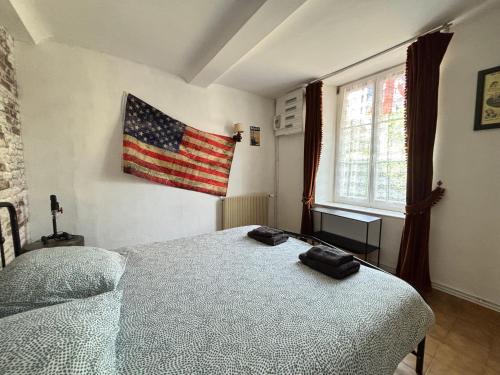 a bedroom with a bed and an american flag on the wall at Les continents maison spacieuse 4 belles chambres parking privatif terrasse à 5 mn à pied tous commerces et 20 mn plage Omaha Beach et à 15 mn de Bayeux in Le Molay-Littry