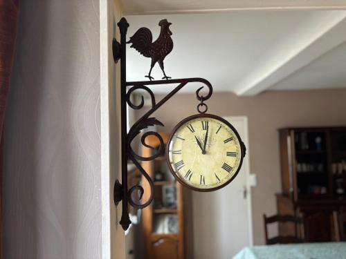 a clock with a chicken on it next to a door at Les continents maison spacieuse 4 belles chambres parking privatif terrasse à 5 mn à pied tous commerces et 20 mn plage Omaha Beach et à 15 mn de Bayeux in Le Molay-Littry