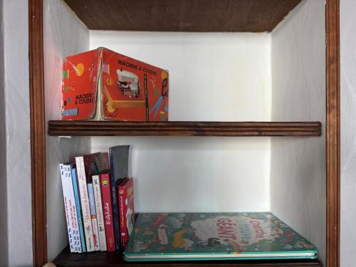 a book shelf with books and a toy on it at Les continents maison spacieuse 4 belles chambres parking privatif terrasse à 5 mn à pied tous commerces et 20 mn plage Omaha Beach et à 15 mn de Bayeux in Le Molay-Littry