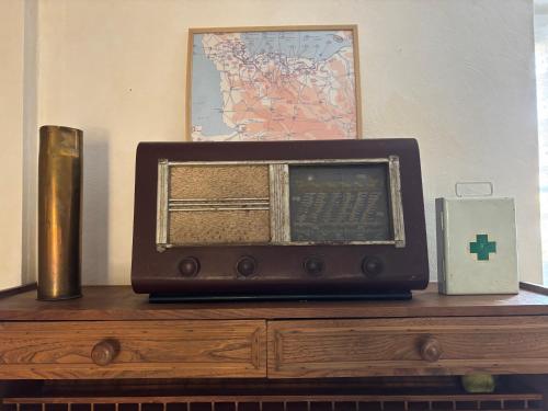 an old radio sitting on top of a wooden dresser at Les continents maison spacieuse 4 belles chambres parking privatif terrasse à 5 mn à pied tous commerces et 20 mn plage Omaha Beach et à 15 mn de Bayeux in Le Molay-Littry