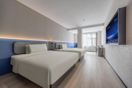 a hotel room with two beds and a flat screen tv at Atour Light Hotel Shandong University Central Campus in Jinan
