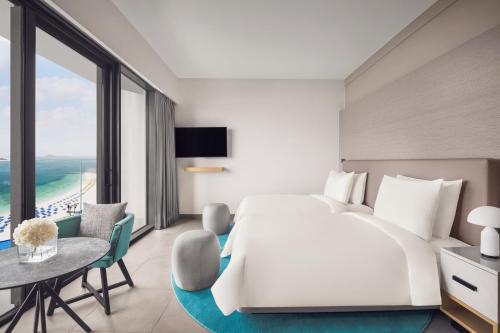 a bedroom with a large white bed and a table at Mövenpick Resort Al Marjan Island in Ras al Khaimah