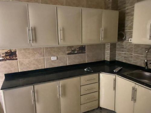 a kitchen with white cabinets and a black counter top at استيلا هايتس الساحل الشمالي in Dawwār ‘Abd al Qādir Qāsim