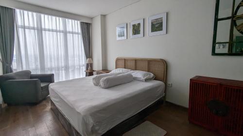 a bedroom with a bed and a chair and a window at Vasaka The Reiz Condo in Medan
