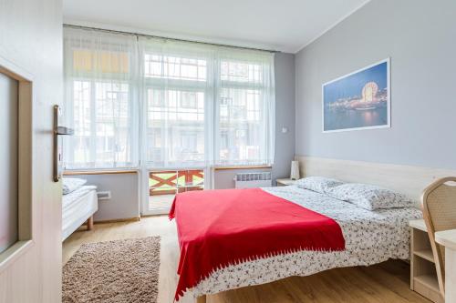 a bedroom with a bed with a red blanket at Apartamenty Zefir in Rowy