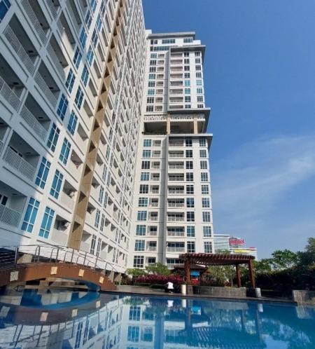 a tall building with a pool in front of a building at Vasaka The Reiz Condo in Medan
