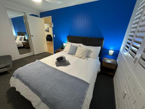 a bedroom with a large bed with a blue wall at Central Cullen Wagga Apartments in Wagga Wagga