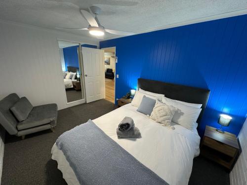 a blue bedroom with a bed and a chair at Central Cullen Wagga Apartments in Wagga Wagga