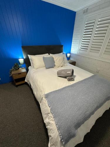 a bedroom with a large bed with a blue wall at Central Cullen Wagga Apartments in Wagga Wagga