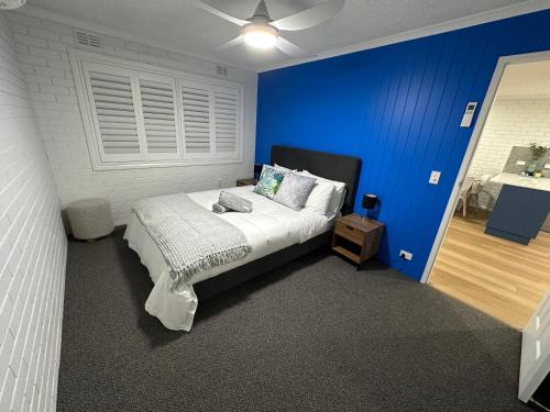 a bedroom with a bed with a blue wall at Central Cullen Wagga Apartments in Wagga Wagga