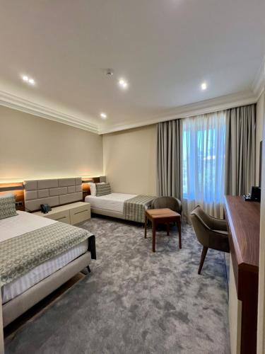 a hotel room with two beds and a desk at Plaza Viktoria Hotel Yerevan in Yerevan