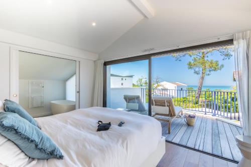 a bedroom with a large white bed and a balcony at Villa Baroya - Villa piscine proche des plages in Bidart