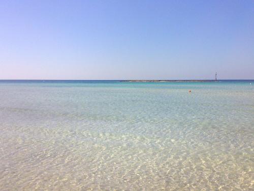 a body of water with a lighthouse in the distance at Dimora Il Girasole in Torre San Giovanni Ugento