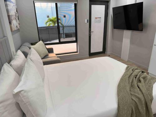 a bedroom with a large white bed and a tv at Belmoral Corporate Suites in Townsville